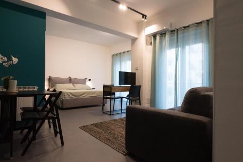 een woonkamer met een bed en een tafel en stoelen bij Oktò apartments Milazzo in Milazzo