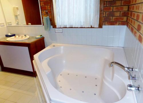 a white bath tub in a bathroom with a sink at Victoriana Motor Inn in Ballarat