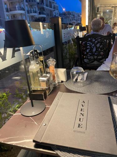 a table with a lamp and a book on it at Hotel AVENUE in Ravda