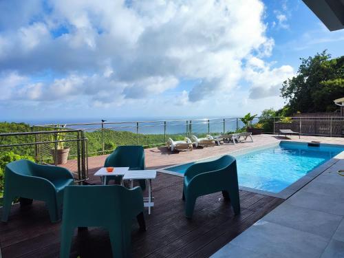a patio with chairs and a pool and the ocean at Villa Madjic in Sainte-Luce