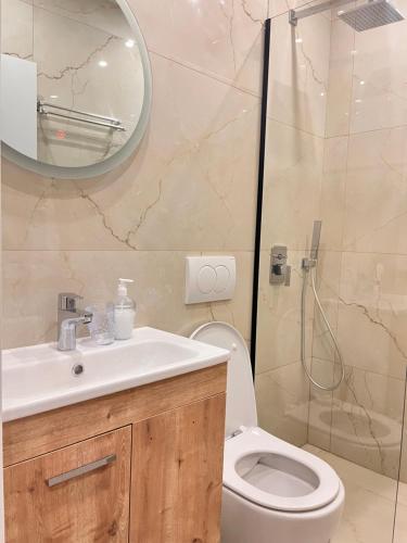 y baño con aseo, lavabo y espejo. en Belix Hotel Apartments, Near the Beach en Durrës