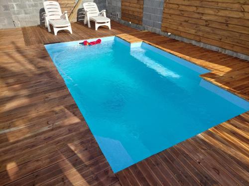 uma piscina com água azul e pisos de madeira em Location saisonnière Bérive em Le Tampon