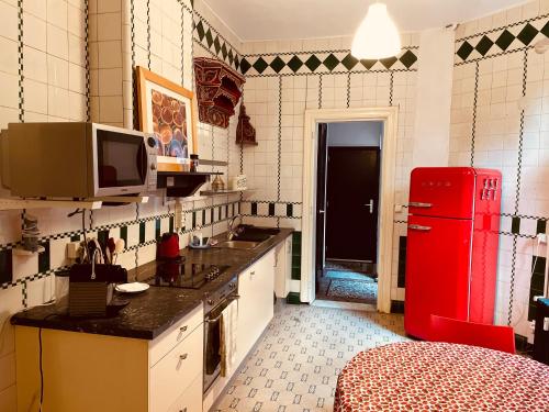 eine Küche mit einem roten Kühlschrank und einem TV in der Unterkunft Magnifique appartement au rdc dans une maison de maître avec cour extérieure in Lüttich