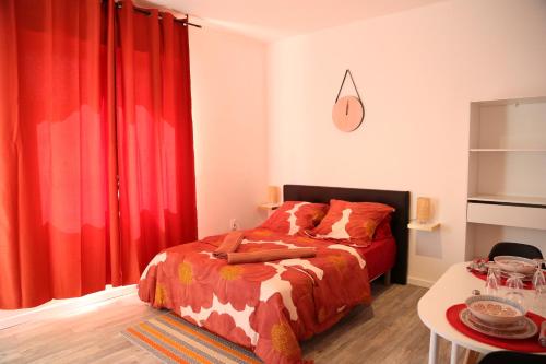 1 dormitorio con 1 cama con cortinas rojas y mesa en Saturne, en Saint-Quentin
