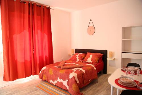 1 dormitorio con cortinas rojas, 1 cama y 1 mesa en Saturne, en Saint-Quentin