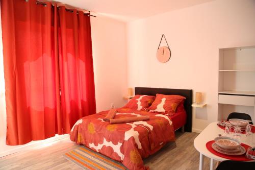 a bedroom with red curtains and a bed and a table at Saturne in Saint-Quentin