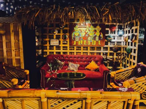 a living room with a red couch and a table at GREEN LEAF GUEST HOUSE in Sreemangal