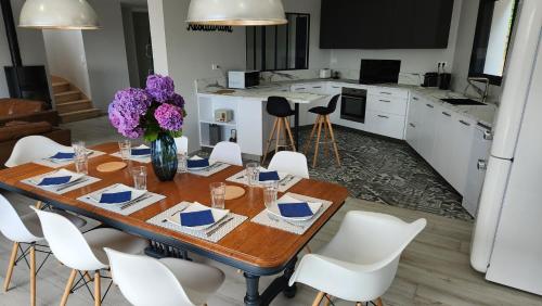 une cuisine et une salle à manger avec une table en bois et des chaises blanches dans l'établissement Villa Ker Bunk, à Audierne