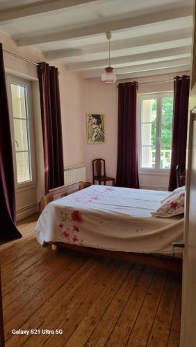 a bedroom with a large bed and two windows at Logis de Pagnolet in Ozillac