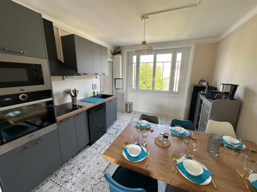 une cuisine avec une table en bois et des chaises ainsi qu'une salle à manger dans l'établissement Chez Tante Muguette proche Dinan, à Le Hinglé