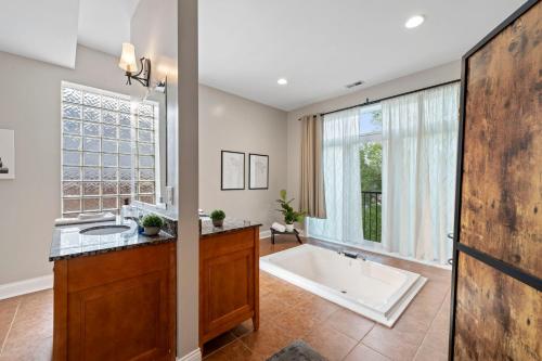 Spacious Luxury Retreat 8 Bed Oasis with 6 Baths في شيكاغو: حمام مع حوض استحمام و نافذة كبيرة