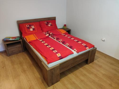uma cama com um edredão vermelho e almofadas vermelhas em Shiny Thumb Apartment em Bihać