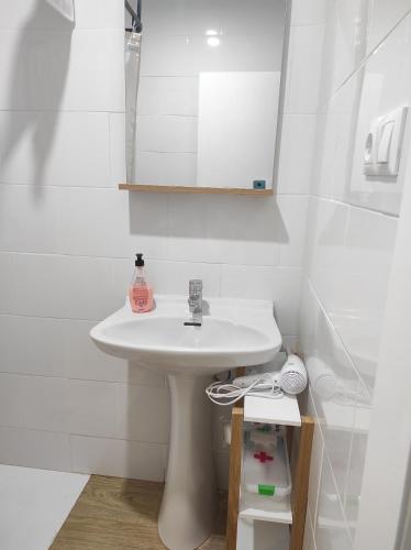 Baño blanco con lavabo y espejo en Apartamentos Can Bruguera 4, en Mataró