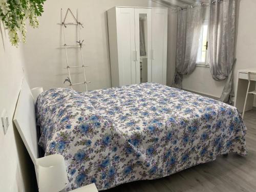a bedroom with a bed with a blue and white blanket at La Petite Maison in Usigliano