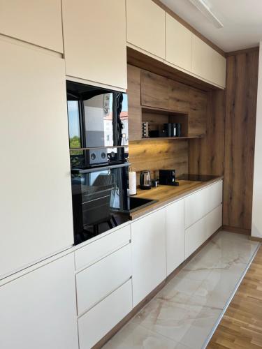 a kitchen with white cabinets and wooden walls at Luxe Living Stara Pazova in Stara Pazova
