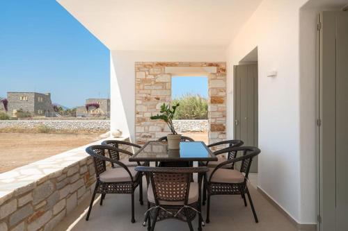 een patio met een tafel en stoelen aan een muur bij Santa Maria Mare in Naousa