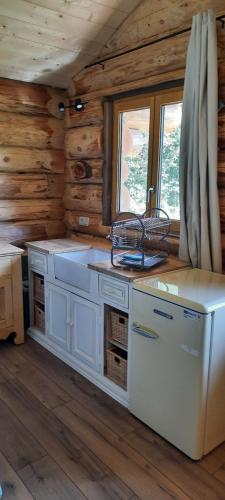 - une cuisine avec des appareils blancs dans une cabane en rondins dans l'établissement Chalet du trappeur, à Grosbreuil