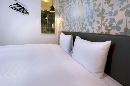 a white bed with white pillows in a room at Queens Hotel II in Taipei