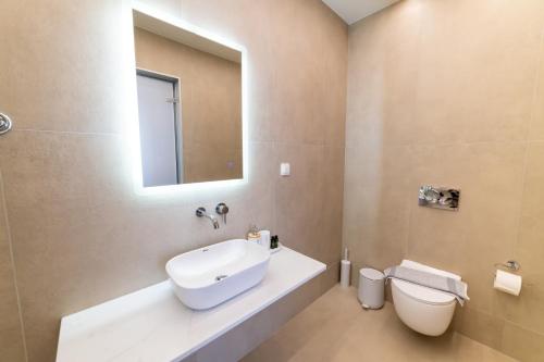 a bathroom with a white sink and a toilet at Lithitsa Lofts and Suites in Parga
