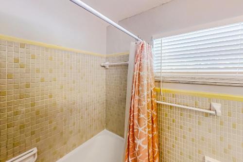 y baño con ducha y cortina de ducha de color naranja. en Dolphin Court #6 en St Pete Beach