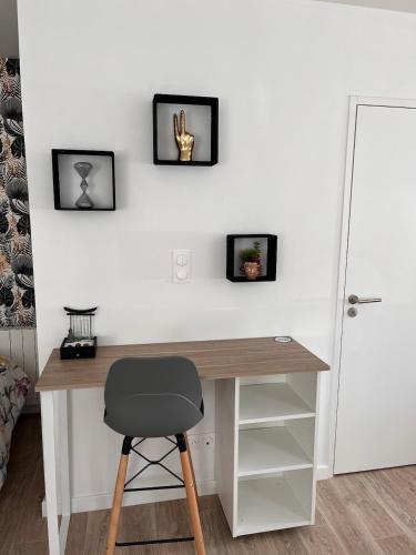 un bureau avec une chaise à côté d'un mur avec deux images dans l'établissement Studio récent, entièrement équipé, proche Chantiers et Airbus, à Saint-Nazaire