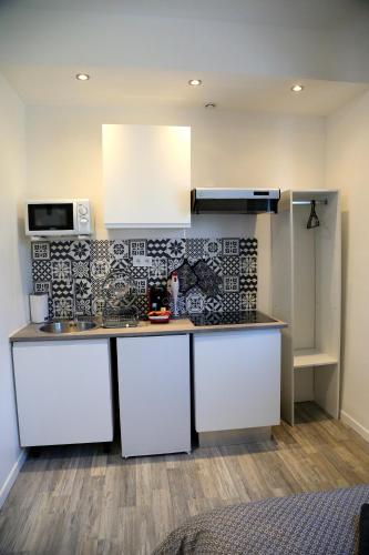 - une cuisine avec un comptoir blanc et un four micro-ondes dans l'établissement Mars, à Saint-Quentin