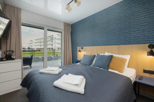 a bedroom with a large bed with towels on it at Grey Apartament - Dziwnów - Basen - SPA - Parking- Taras in Dziwnów