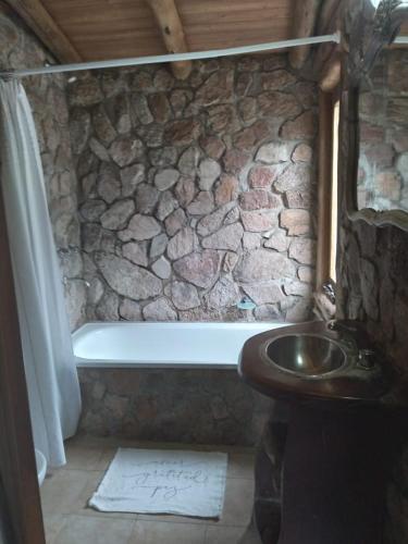 a stone bathroom with a bath tub and a sink at Rincón Alto Cabañas in Nono