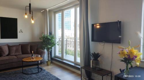 ein Wohnzimmer mit einem Sofa und einem großen Fenster in der Unterkunft Be my Guest - Jerozolimskie Studio - Super Centrum Metro Wi-Fi Breakfast in Warschau