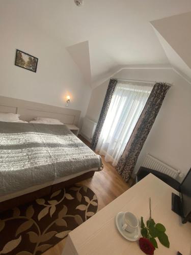a bedroom with a bed and a table and a window at Pensiunea Cassandra in Neagra Şarului