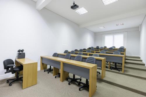 a classroom with desks and chairs in a room at Le Village Flats e Hotel in Joinville