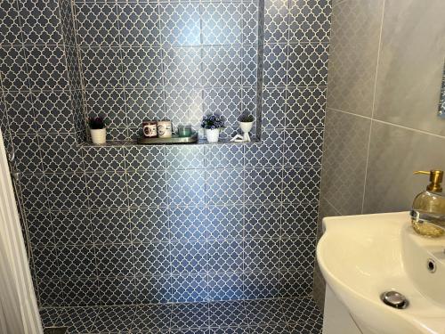 baño con ducha y pared de azulejos azules en Yiayia Katina’s House, en Korinthos