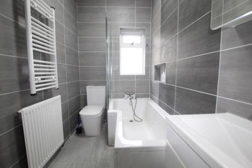 uma casa de banho com uma banheira, um WC e um lavatório. em Friendly Stockport em Stockport