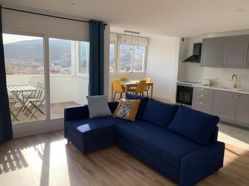 sala de estar con sofá azul y cocina en ATICO PASEO DE ALMERÍA en Almería