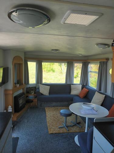 a living room with a couch and a table at Carn Kenidjack View Caravan, space, peace and tranquillity in Penzance