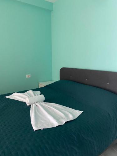 a green bed with two white towels on it at Alma Rose Apartment in Korçë