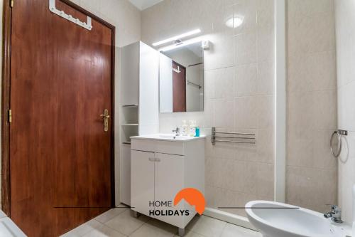 La salle de bains est pourvue d'un lavabo, de toilettes et d'une porte en bois. dans l'établissement #167 Kid Friendly New Town with Pool and Balcony, à Albufeira