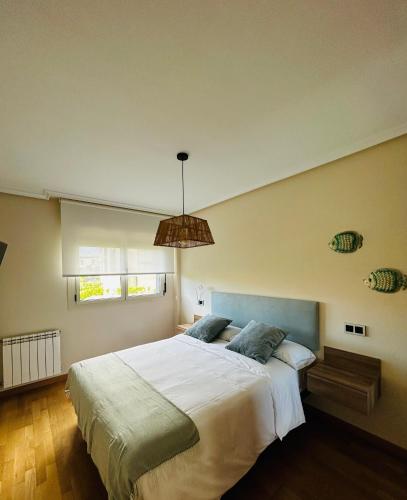 a bedroom with a large bed and a pendant light at MARINA LLANES V in Llanes