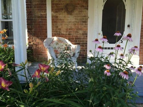 a chair sitting outside of a house with flowers at Wine Country 4 bedrooms in Wellington