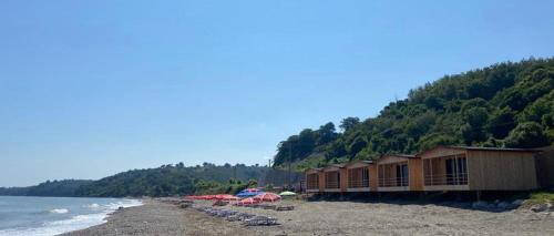 einen Strand mit einer Reihe von Häusern und Sonnenschirmen in der Unterkunft Black Sea Beach Bungalow in Akcakoca