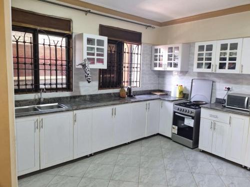 cocina con armarios blancos y fogones en Lovely 2 _ bedroom unit, en Kampala