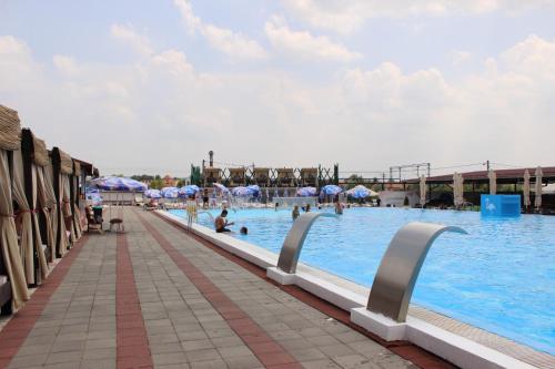a swimming pool with people in the water and umbrellas at Flamingo Resort in Belgrade