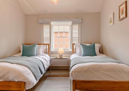 紹斯沃爾德的住宿－Mariners Cottage - Southwold，带窗户的客房内的两张床
