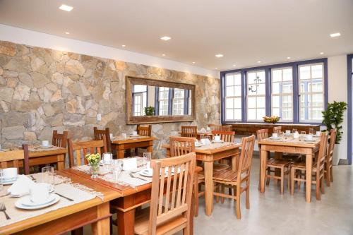 a restaurant with wooden tables and chairs and a stone wall at Pousada Pouso de Laura in Tiradentes