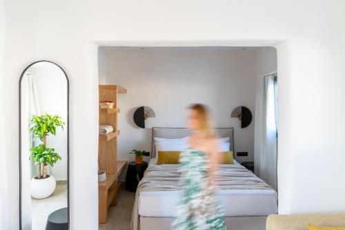 a person in a bedroom with a bed and a mirror at Enalios sunset suites in Naxos Chora
