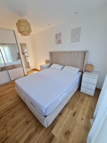 a bedroom with a large white bed and wooden floors at Charmante Villa moderne in Pornichet