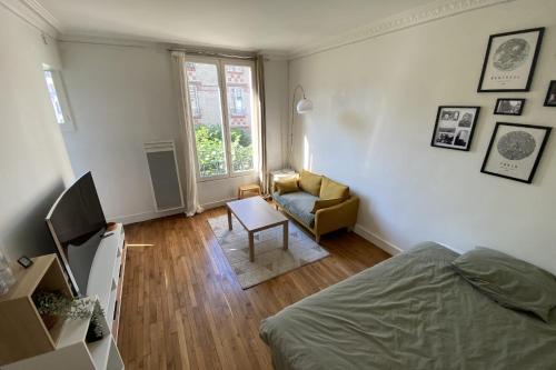um quarto com uma cama, uma cadeira e uma janela em Cozy love nest near the Seine em Issy-les-Moulineaux