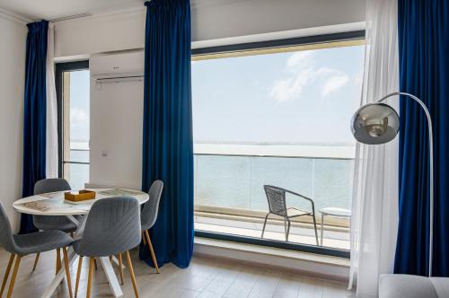 jadalnia ze stołem i krzesłami oraz dużym oknem w obiekcie Azure Sea Apartments - ByChoice w Mamai