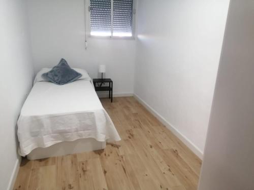 a white bedroom with a bed and a wooden floor at 2 bedroom Apartment in San Fernando in San Fernando