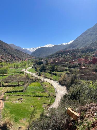 a river in a field with mountains in the background at Tazart Lodge in Marrakech